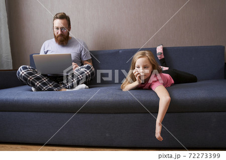 Girl laying at the sofa near her handsome bearded father 72273399