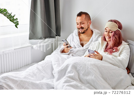 caucasian couple using smartphone lying on bed together, checking social networks news caucasian couple using smartphone lying on bed together, checking social networks news 72276312