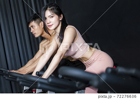 Young woman and friends on fitness bike in gym during workout 72276636