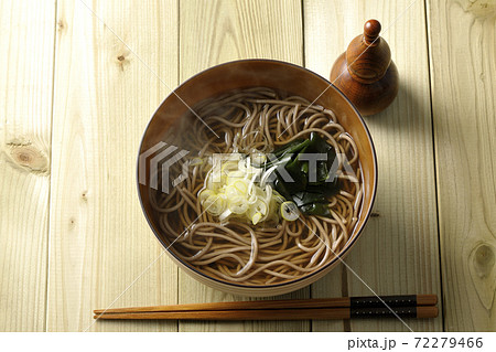 刻み葱とわかめがトッピングされたシンプルな掛け蕎麦と瓢箪型の七味入れ（俯瞰） 72279466