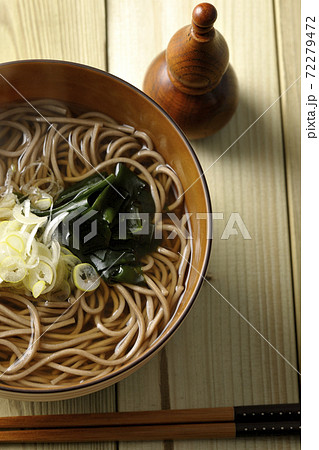刻み葱とわかめがトッピングされたシンプルな掛け蕎麦と瓢箪型の七味入れ（俯瞰） 72279472