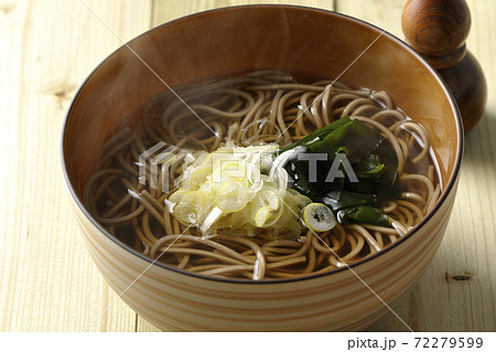 刻み葱とわかめがトッピングされたシンプルな掛け蕎麦と七味入れ 72279599