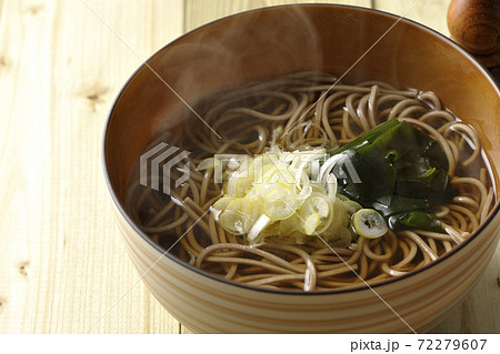 刻み葱とわかめがトッピングされたシンプルな掛け蕎麦と七味入れ 72279607