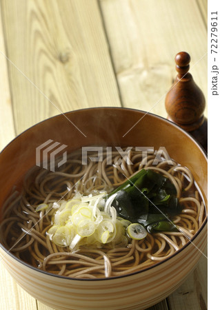 刻み葱とわかめがトッピングされたシンプルな掛け蕎麦と七味入れ 72279611