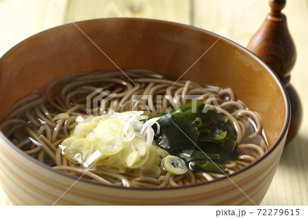 刻み葱とわかめがトッピングされたシンプルな掛け蕎麦と七味入れ 72279615