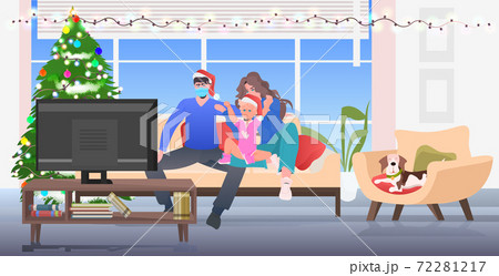 family spending time together parents with daughter in santa hats watching tv at home new year christmas holidays family spending time together parents with daughter in santa hats watching tv at home new year christmas holidays 72281217