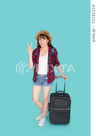 Beautiful young asian woman pulling suitcase isolated on blue background. Beautiful young asian woman pulling suitcase isolated on blue background. 72282219