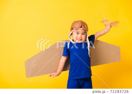 Kid little boy smile wear pilot hat play and goggles with toy cardboard airplane wings 72283726