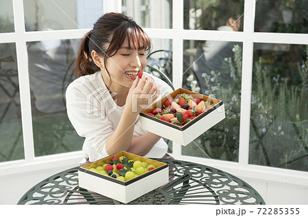 フルーツの詰め合わせに喜んで食べようとしている女性 フルーツの詰め合わせに喜んで食べようとしている女性 72285355