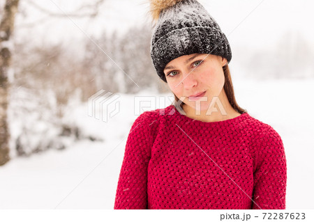 Girl in red in a snowy park in winter when it snows. 72287623