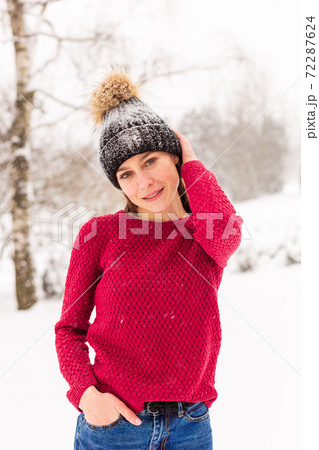 Girl in red in a snowy park in winter when it snows. 72287624