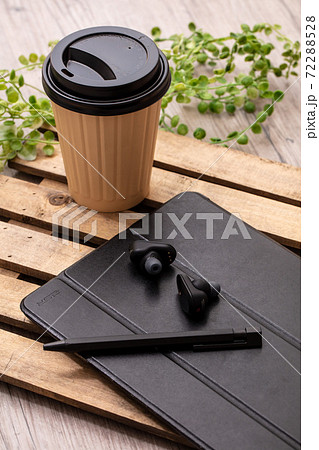 飲み物と黒いイヤホンとタブレット端末が木製の机に置いてある Tablet Cofee Earphonの写真素材