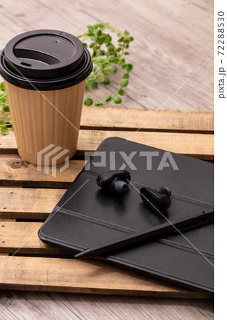 飲み物と黒いイヤホンとタブレット端末が木製の机に置いてある Tablet Cofee Earphonの写真素材