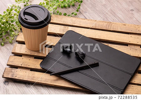 飲み物と黒いイヤホンとタブレット端末が木製の机に置いてある Tablet Cofee Earphonの写真素材