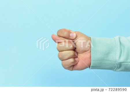 Male hand showing a fig gesture sign on blue background 72289590