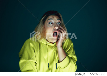 Close up portrait of young crazy scared and shocked woman isolated on dark background Close up portrait of young crazy scared and shocked woman isolated on dark background 72292029