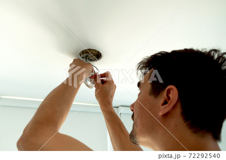 Man hands installing socket for light bulb. Repairs ceiling light indoor home in white room 72292540