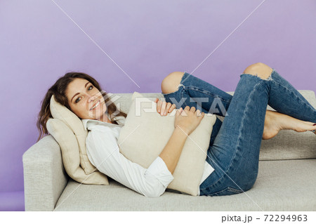 Beautiful woman sits on a gray office sofa in a white house room 72294963