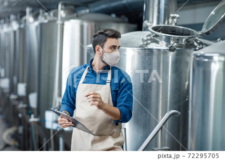 Factory employee works with equipment for industrial beer production 72295705