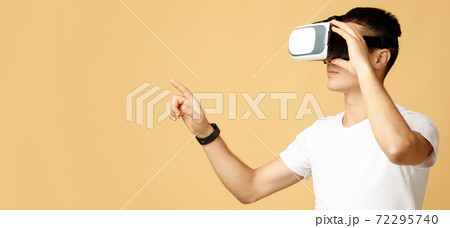 Serious young guy student in white t-shirt and virtual reality glasses touches to free space 72295740
