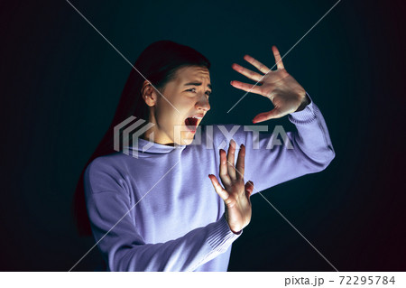 Close up portrait of young crazy scared and shocked woman isolated on dark background Close up portrait of young crazy scared and shocked woman isolated on dark background 72295784