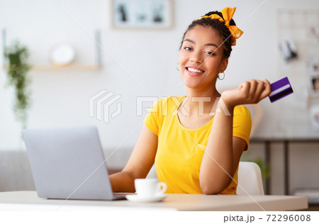 Black woman using laptop and credit card at home Black woman using laptop and credit card at home 72296008
