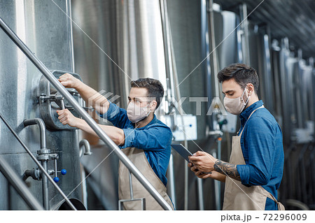 Workers at brewery and fermentation of beer to produce beverage Workers at brewery and fermentation of beer to produce beverage 72296009