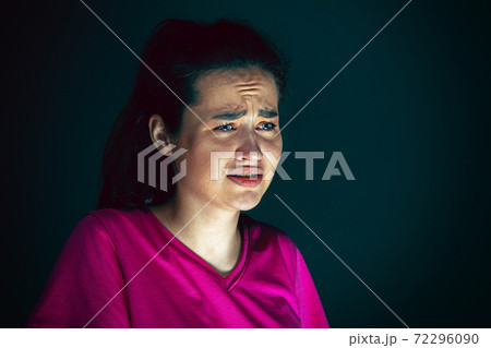 Close up portrait of young crazy scared and shocked woman isolated on dark background Close up portrait of young crazy scared and shocked woman isolated on dark background 72296090