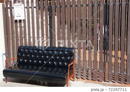 Black leather sofa and wooden armrest chair with white mailbox on brown background 72297711