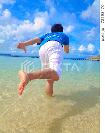 真夏の沖縄の海で駆け出す青年の写真素材