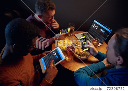 Excited fans with mobile app for betting and score on their devices. Gambling, emotions Excited fans with mobile app for betting and score on their devices. Gambling, emotions 72298722