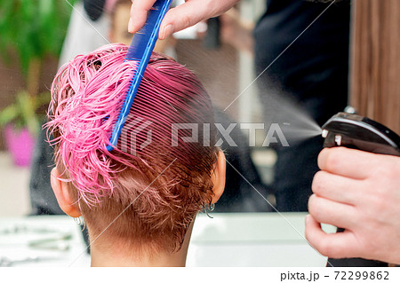 Hairdresser sprinkles water on hair. 72299862