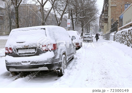 City after blizzard. Cars parked on a street covered with snow. City after blizzard. Cars parked on a street covered with snow. 72300149