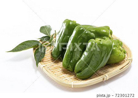 白バックでざるの上に葉を添えて並べたピーマン 72301272