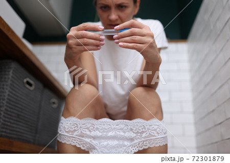 Woman sit on toilet and hold test in her hands for take analyzes. 72301879