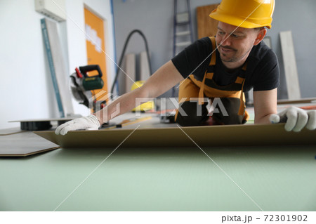 Man hold laminate panel and lay on floor on soft pad in room. 72301902