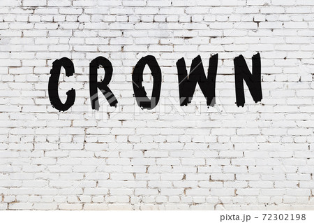 Word crown painted on white brick wall 72302198