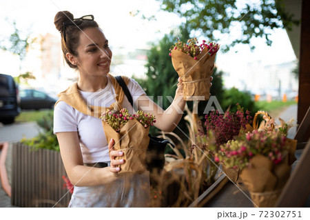 happy caucasian young woman chooses potted flowers to buy at outdoor garden stall happy caucasian young woman chooses potted flowers to buy at outdoor garden stall 72302751
