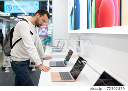 Belarus; December 05, 2020; a man chooses a laptop in an Apple technology store, new laptops on the 72302829
