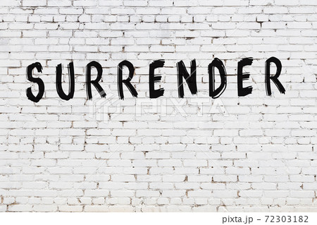 Word surrender painted on white brick wall 72303182