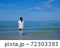 Back side of a girl standing in the sea looking at the horizon. 72303393