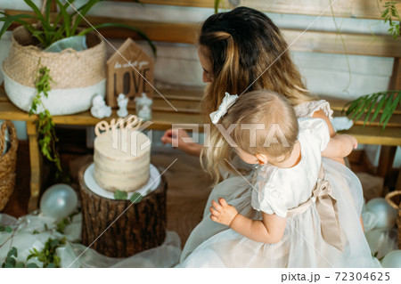 Happy family celebrating first birthday of baby daughter with cake. 1st Birthday home party ideas with natural decoration. Sustainable eco-friendly baby birthday at home 72304625