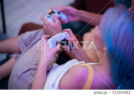 Young couple playing video games while sitting on the living room floor lit with neon color. Young couple playing video games while sitting on the living room floor lit with neon color. 72304992