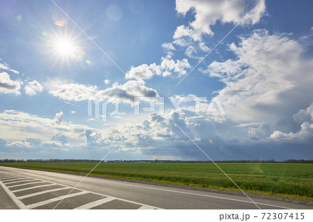 Asphalt highway with road markings on the background of blue sky and clouds Asphalt highway with road markings on the background of blue sky and clouds 72307415