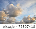 Fluffy clouds backlit by the sun at sunset 72307418