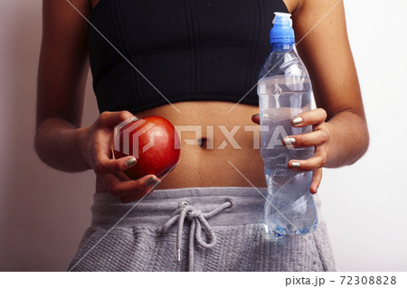 close up woman stomach with hands holding water and red apple on white background 72308828