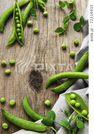 Pods of green peas with pea leaves on a old wooden background. Organic food. Pods of green peas with pea leaves on a old wooden background. Organic food. 72316935