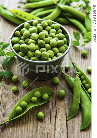 Fresh green peas in a small metal bucket on old wooden background. Fresh green peas in a small metal bucket on old wooden background. 72316940