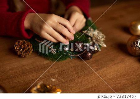 little child girl makes a handmade Christmas wreath 72317457