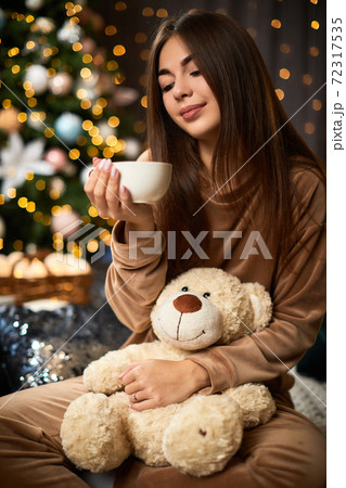 Happy young woman is holding cup of coffee Happy young woman is holding cup of coffee 72317535